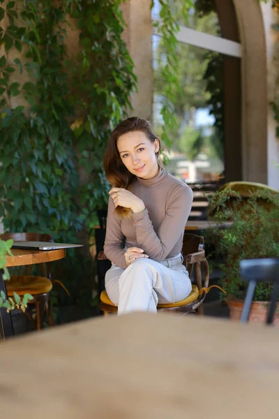 若いですcaucaisian女性ポージングにストリートカフェ,閉じノートパソコン上のテーブル. — ストック写真