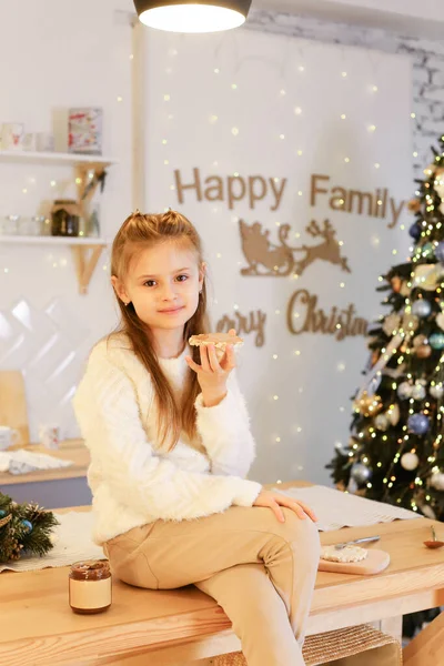 Молода дівчина їсть арахісове масло на Різдвяному фоні — стокове фото