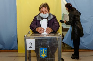 Velyka Dobron, Ukrayna - 25 Ekim 2020: Koronavirüs salgını sırasında yerel seçimlerde koruyucu maskeli yaşlı kadın oy kullandı.