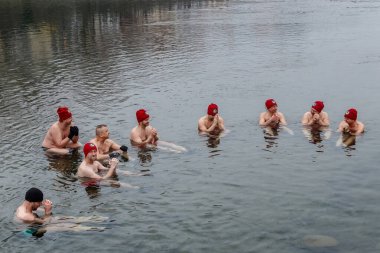 Uzhgorod, Ukrayna - 19 Ocak 2020: Bir grup insan Ukrayna 'daki geleneksel Epifani kutlamaları sırasında buzlu nehirde banyo yapıyor.