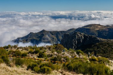 Bulutlar, engebeli arazileri ve karanlık gölgeleriyle huşu uyandıran görkemli dağları sarıyor. Madeira adasında Pico do Arieiro 'nun tepesinden görünüm (Portekiz).
