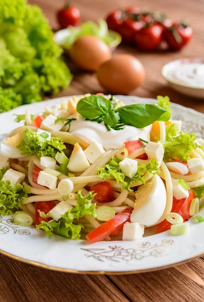 Salată de paste de spaghete cu roșii, salată verde, ou, brânză Feta, ceapă verde și smântână — Fotografie, imagine de stoc