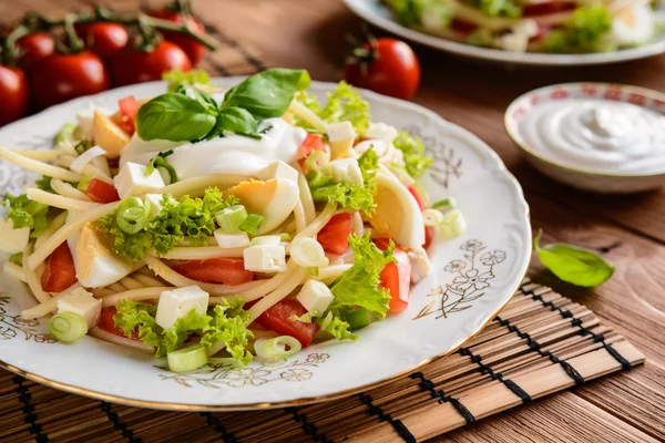 Spaghetti-Nudelsalat mit Tomaten, Salat, Ei, Feta-Käse, grünen Zwiebeln und saurer Sahne — Stockfoto