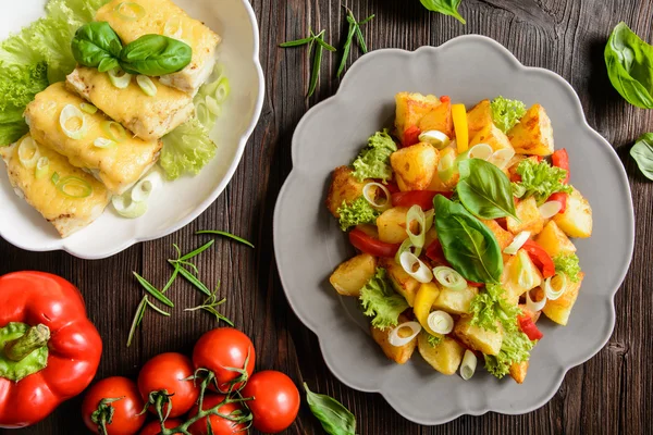 Salada de batata frita com alface, pimenta, cebola e filetes de peixe assados cobertos com queijo — Fotografia de Stock