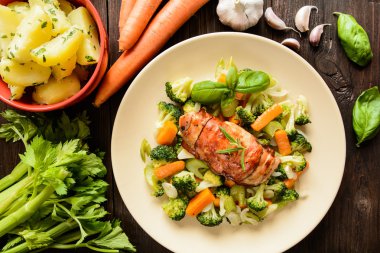 Fırında tavuk göğsü pastırma haşlanmış patates ile sarılmış ve haşlanmış sebze garnitür