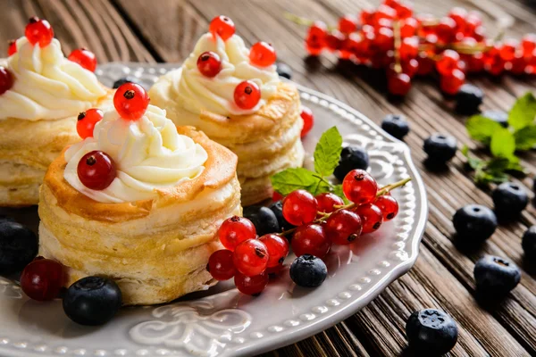 Puff pastry cakes filled with whipped cream and berries — Stock Photo, Image