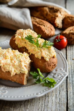 Yumurta, havuç, yeşil soğan, salatalık turşusu ve mayonez bir kepek ekmeği baget üzerinde yayılmış lor