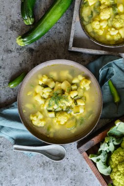Tasty green cauliflower and zucchini soup with diced potatoes for lunch clipart