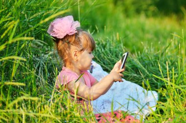 küçük kız bir smartphone ile oynamak.