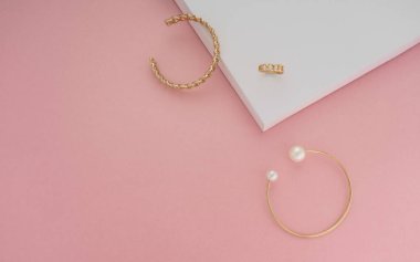 Pembe ve beyaz arka planda altın mücevherlerin en üst görüntüsü