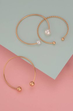 Pastel arka planda üç altın bileziğin dikey çekimi