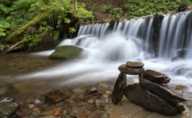 Dağ nehrindeki şelalenin yanına istiflenmiş taşlar.