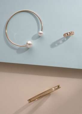 Mavi ve bej arkaplanda altın bilezikler ve yüzük