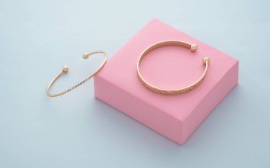 Mavi arkaplandaki pembe kutuda iki altın bilezik.