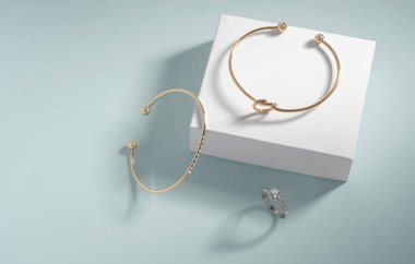 Fotokopi alanı beyaz ve mavi arkaplanda modern altın bilezikler ve elmas yüzük