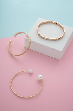 Pastel renkli kağıt arka planda modern altın bileziklerin dikey çekimi