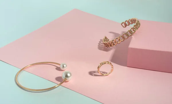 Forma de corrente e ouro com pulseiras de pérola e anel em papel rosa e verde — Fotografia de Stock