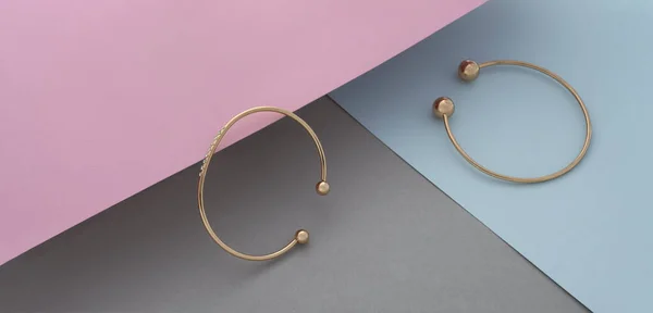 Panorama dwóch nowoczesnych złotych bransoletek z diamentami na pastelowym tle koloru z przestrzenią do kopiowania — Zdjęcie stockowe