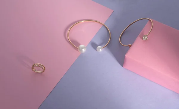 Современный золотой с жемчугом и бриллиантами браслеты на розовом и фиолетовом фоне бумаги — стоковое фото