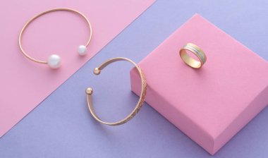Modern altın bileziklerin üst görünümü ve pastel renkler üzerinde halka kağıt arkaplan kopyalama alanı ile