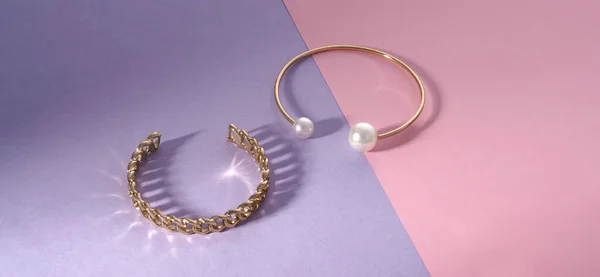 Panorama en forme de chaîne et doré avec des bracelets en perles sur papier rose et violet — Photo