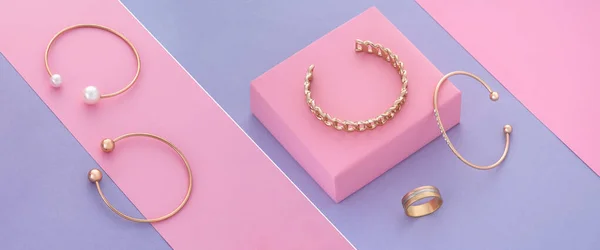Collar de fotos inclinado de pulseras de oro y anillo sobre fondo de colores pastel — Foto de Stock