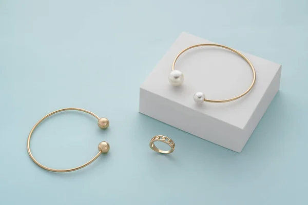 Золотой с кожурой браслет на белой коробке и золотой браслет и кольцо с копировальным пространством — стоковое фото