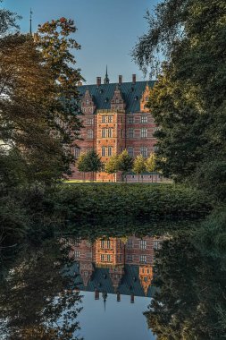 Ormandaki Royal Frederiksborg kalesi 17 Ekim 2020 'de Danimarka' nın Hillerod kentinde bulunan ayna gibi parlak bir gölete yansıtılır.