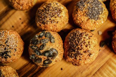 Freshly baked whole grain rolls with various seeds such as pumpkin, sesame and flax on wooden background