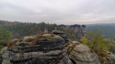 Atmosferik seyahat videosu Almanya 'nın Sakson İsviçre kentindeki ünlü Bastei Köprüsü' nü gösteriyor. Sis, yağmur ve sonbahar renkleri kumtaşı kayalıkları ve orman vadisi üzerinde dramatik bir hava yaratır..