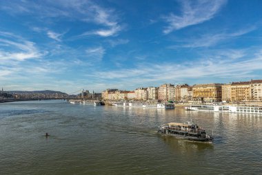 Tuna Nehri 'nden Budapeşte manzarası. Mavi gökyüzünün altında tarihi nehir kıyısında binalar var.