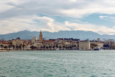Hırvatistan 'ın Split kentinin panoramik manzarası, mavi gökyüzünün altında palmiye çizgili gezinti güvertesi, eski kasaba ve katedral kulesi