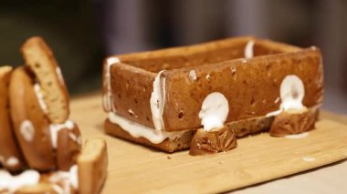 Yakın çekim videoda, torunlarına Noel pastası pişirme geleneğini, sıcaklığı, sevgiyi ve sevgiyi yansıtan kremayla zencefilli ekmek treni kuran dedelerin nazik ellerini görüyoruz.