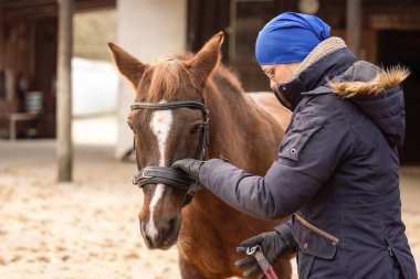 Kestane atını kış taarruzu için hazırlarken hamlesini ve mağara yolunu tutan kadın.