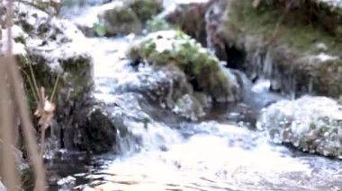 Soğuk arazi boyunca kar ve buz saçakları akan küçük kış akıntısı