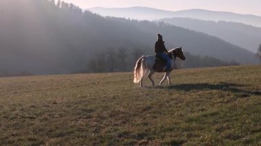 Açık bir çayırda at süren iki kadın barışçıl kırsal alanda birbirini takip ediyor.