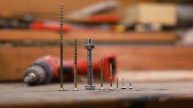 Bir atölyedeki tezgahta duran farklı vidaları kapatın, boyut, metal doku ve sıralamayı gösterin