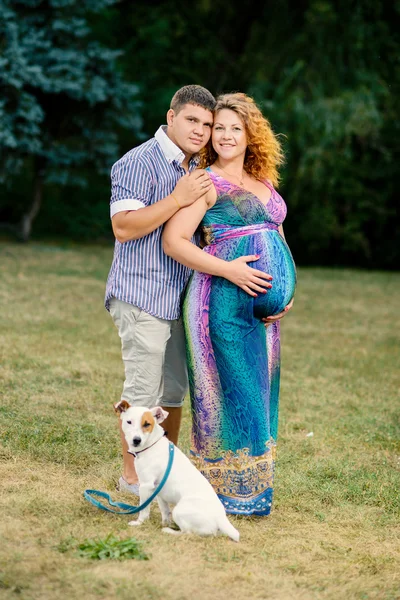 Šťastné a veselé dvojice se psem v parku. Žena je těhotná. Zaměřit se na lidi — Stock fotografie