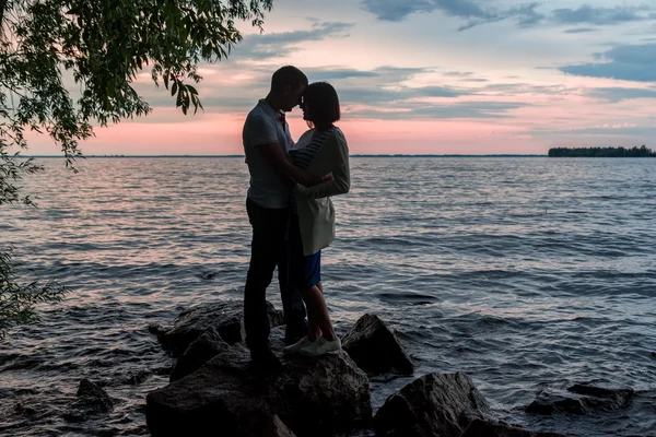 Siluet dari pasangan romantis pada latar belakang matahari terbenam di dekat air — Stok Foto