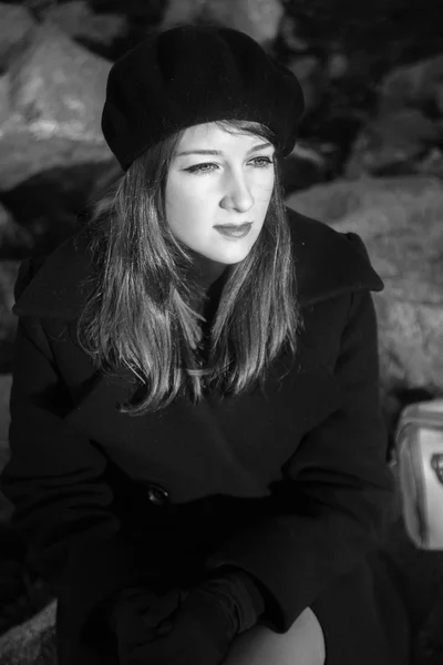 Fekete-fehér portré egy lány ült a sziklák az őszi — Stock Fotó