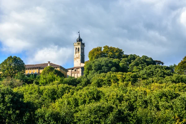 La vieja torre con una campana en el extremo del campo contra el telón de fondo de nubes gruesas. Italia — Foto de Stock