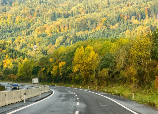 Herbstautobahn zwischen den Bäumen auf dem Hügel. — Stockfoto