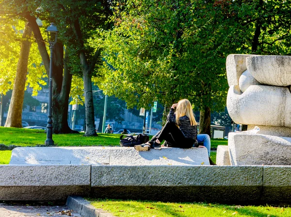 Chica rubia relajándose en el parque sentado en la piedra blanca en Milán. Italia . — Foto de Stock