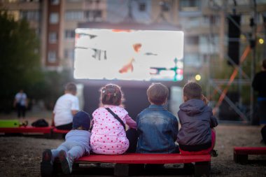 Açık hava sineması. Çocuklar bir yaz sinemasında film izliyorlar.