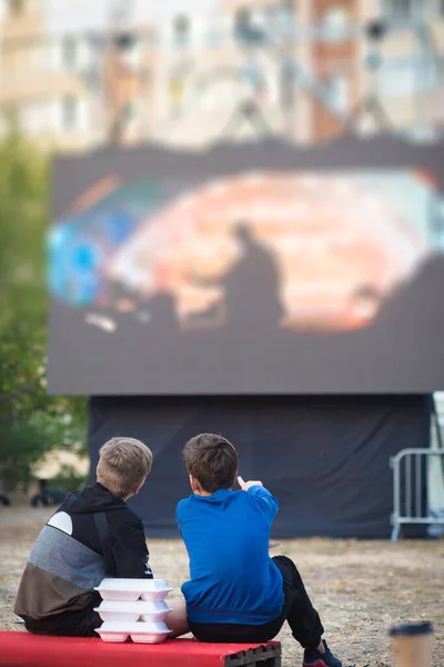 Open-air cinema. Children watching a movie on the screen of a summer cinema