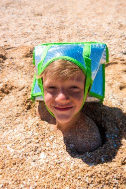 Çocuğun kafası kuma saplanmış durumda. Kafama serin bir torba geçirerek..