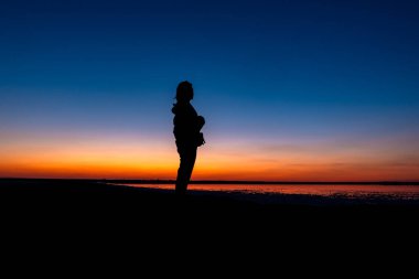Gün batımında kadın silueti. Uzağa bakan kadın.