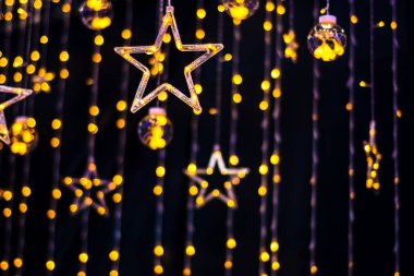 Karanlık bir arka planda Noel çelenkleri ve yıldızlar..