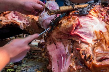 Şef kızarmış domuz etiyle bıçak kesiyor.