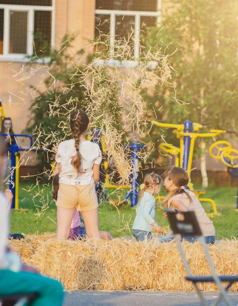 少女は干し草を投げ上げた 屋外で遊ぶ子供たち — ストック写真